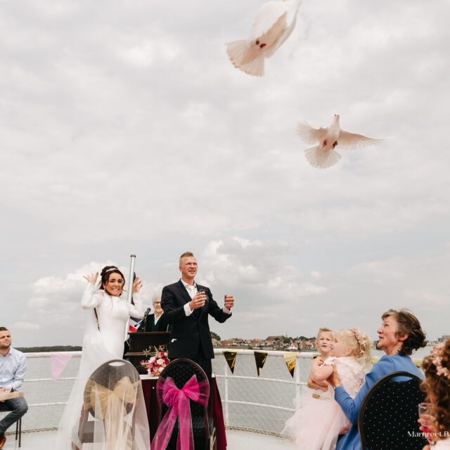 bruidspaar die duiven loslaat op urkerboot na ceremonie